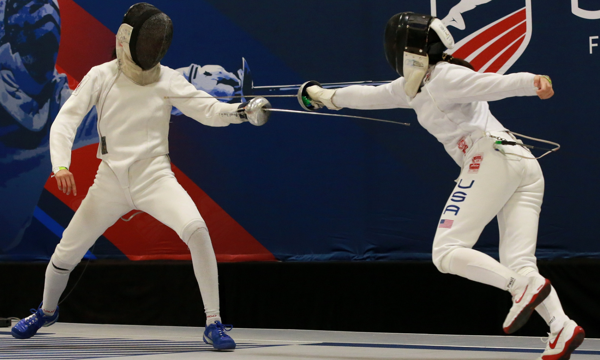 Two fencers compete on the strip in a fencing match.